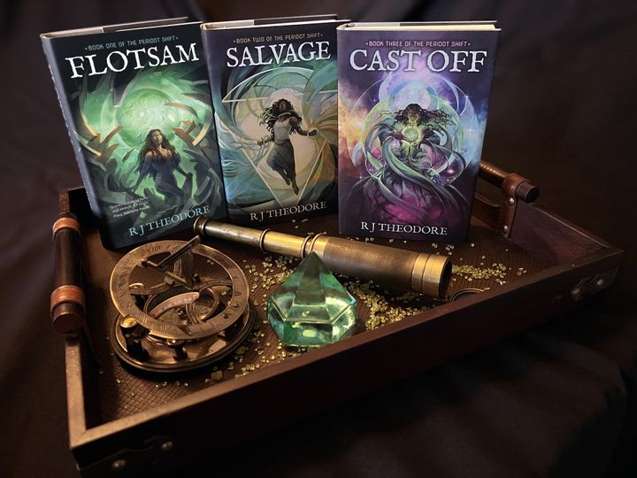 Flotsam, Salvage, and Cast Off stand on a tray with a big gem, some small peridot pebbles, a spyglass, and an astrolabe.